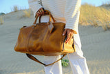 COFFT DUFFLE 01 Latte leather duffle bag carried on sand dunes with soft golden light and travel styling