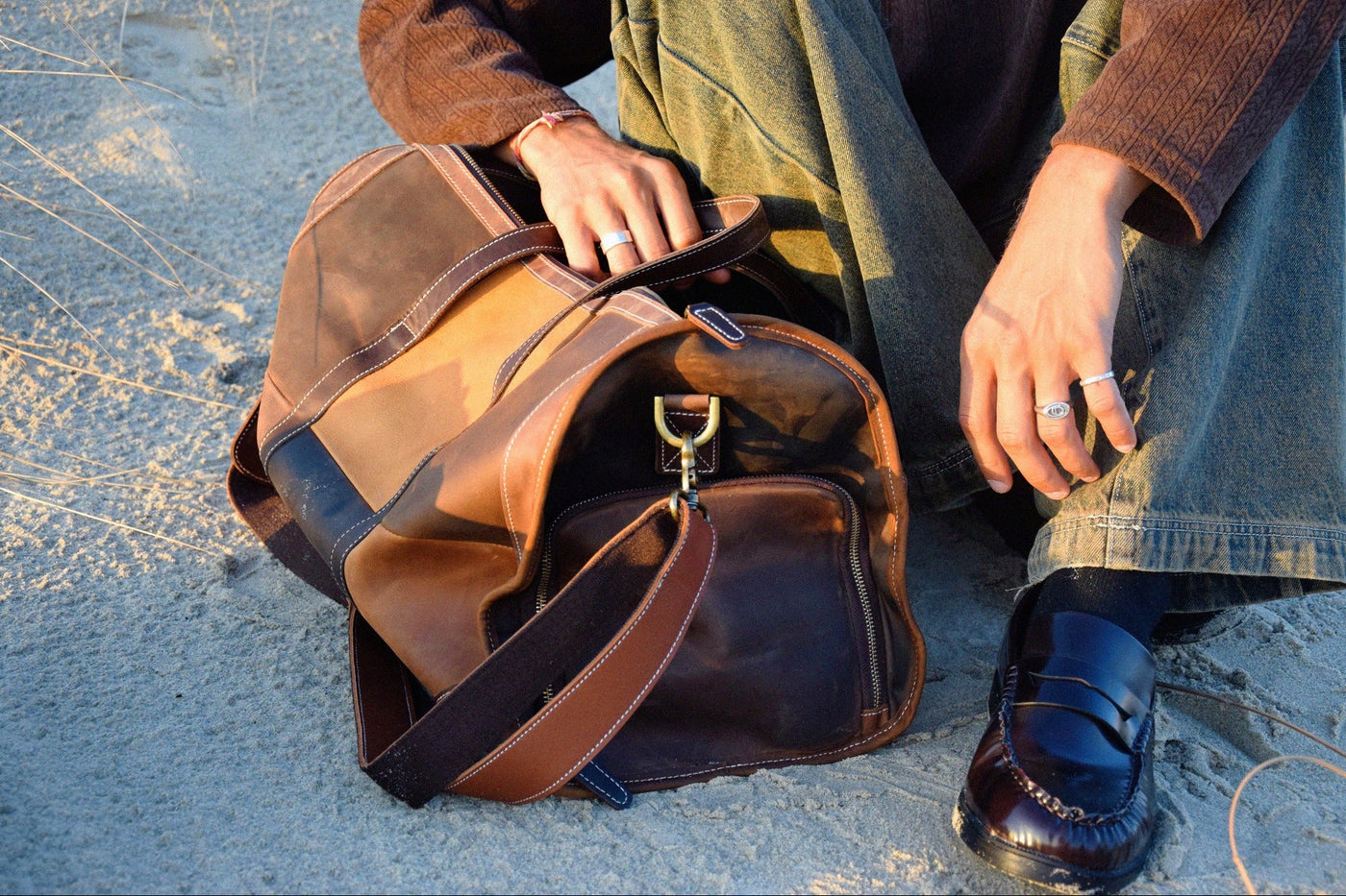 COFFT Signature patchwork leather duffle bag with side compartment open in a relaxed beach lifestyle scene