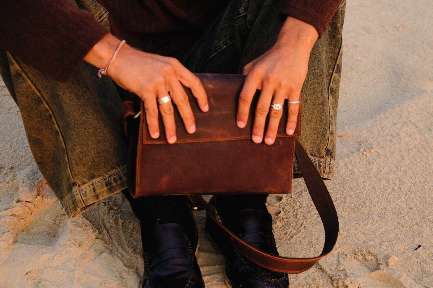 COFFT Espresso leather messenger bag front view on sand with shoulder strap and minimalist lifestyle styling