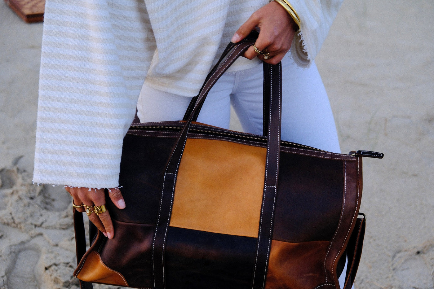 COFFT Signature patchwork leather duffle bag carried by hand with Latte and Espresso panels