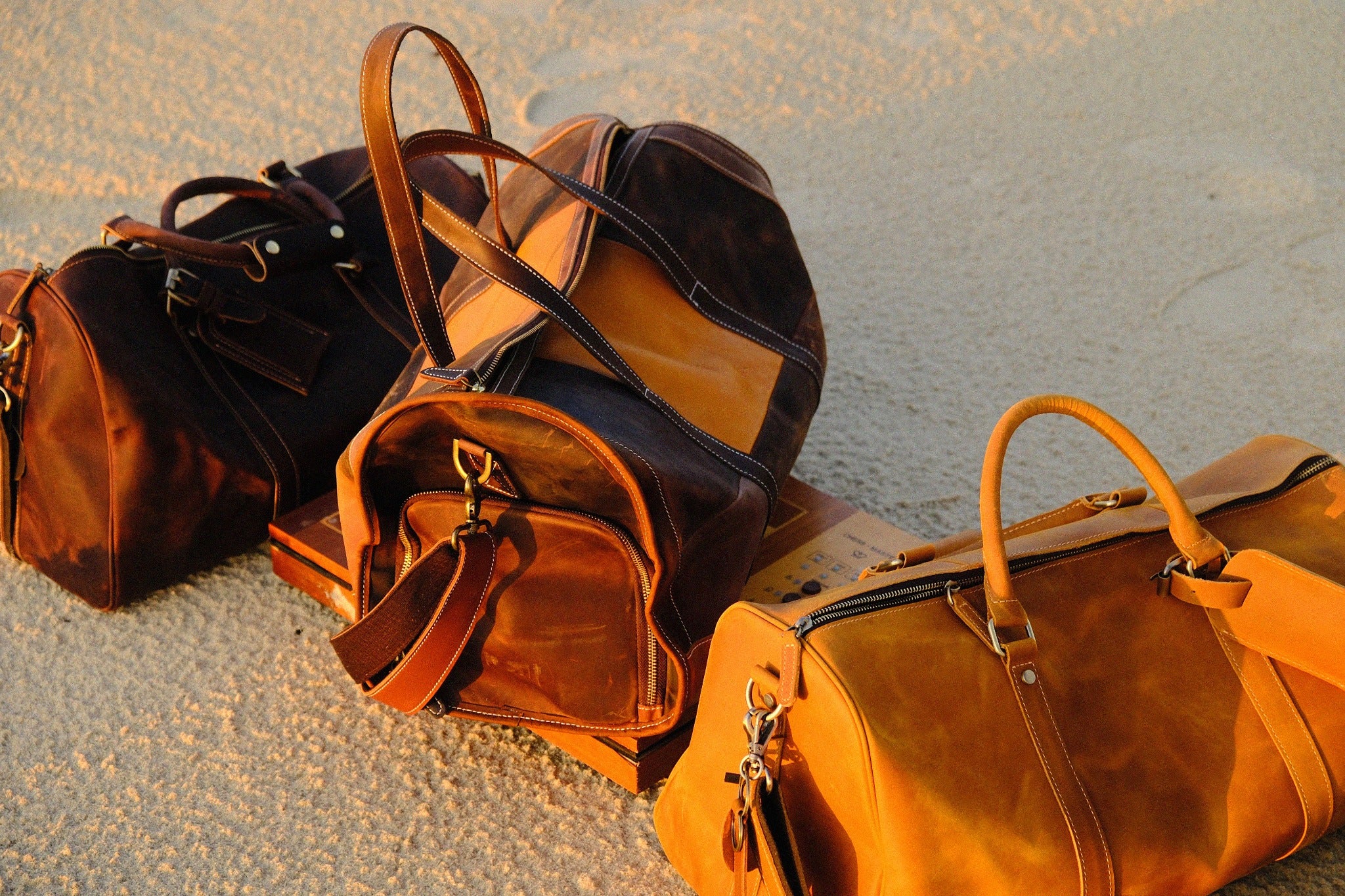 COFFT Signature and DUFFLE 01 leather bags in Latte and Espresso styled with a chessboard on sand