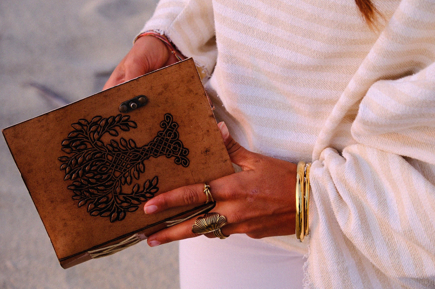 COFFT leather notebook with brown cover and black artwork detail, held with a minimal white outfit