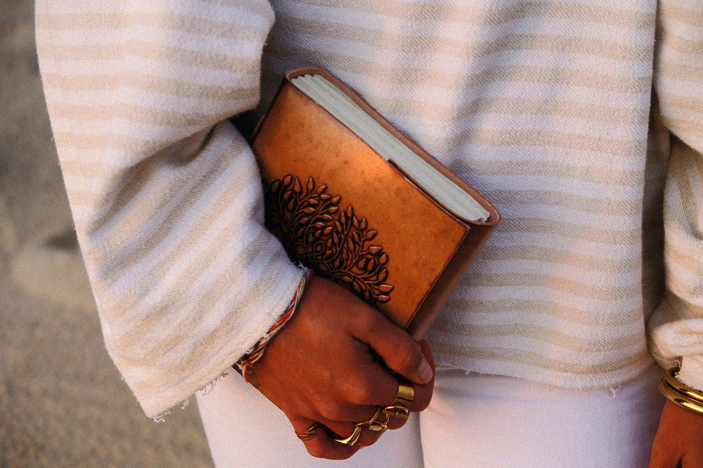 COFFT leather notebook held against a white outfit, showing brown cover, soft edges and everyday lifestyle use