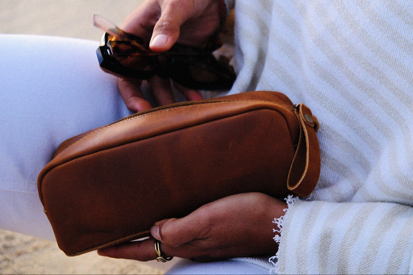 COFFT Latte leather pouch styled with sunglasses in a close-up lifestyle scene with soft neutral tones