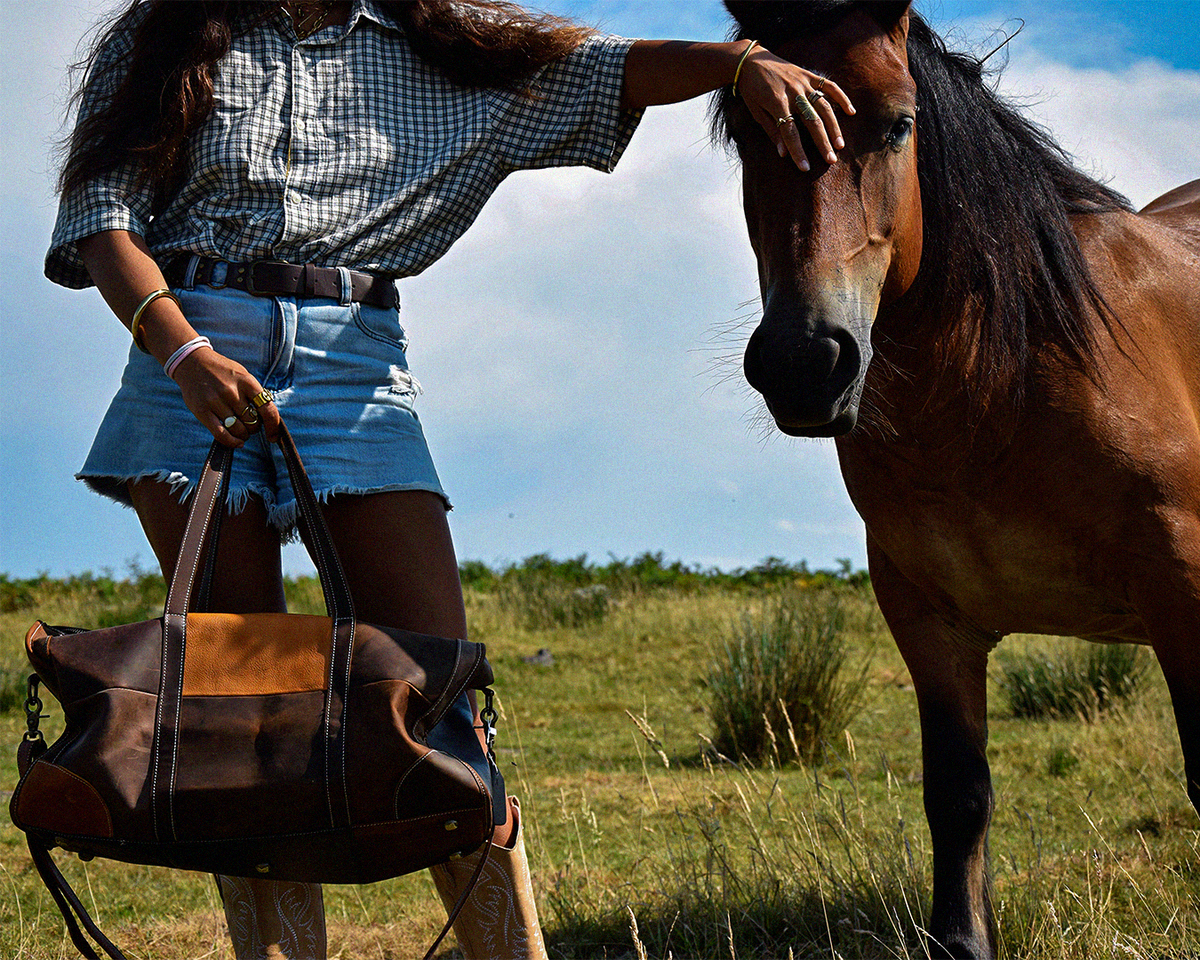Woman touching a horse's face while holding the COFFT Signature Patchwork Duffle, Patchwork colorway